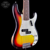 A classic four-string electric bass guitar with a sunburst finish, featuring a white pickguard and chrome hardware, photographed against a solid black background with a Tone Shop watermark in the top left corner.