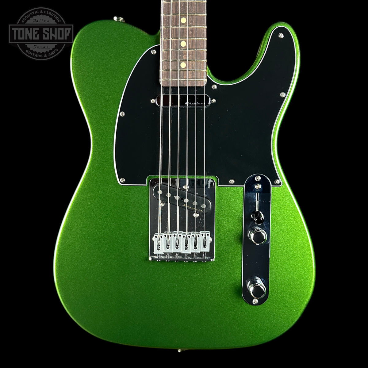 A green metallic electric guitar with a black pickguard and chrome hardware, shown against a solid black background with a Tone Shop watermark in the top left corner.