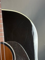 Close-up of an acoustic guitar's soundhole and neck against a dark background