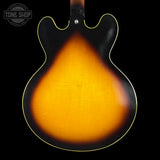 The back of an electric guitar with a classic sunburst finish, showing a bright orange center fading to black around the edges, with a gold-toned binding and a Tone Shop logo in the top left corner.