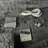 Guitar pickup, clip-on tuner, and cable on a textured surface