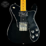 Black electric guitar with a clear body on a black background, featuring the Tone Shop logo.