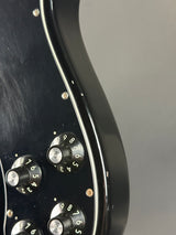 Close-up of a guitar's control knobs on a black guitar body with a gray background