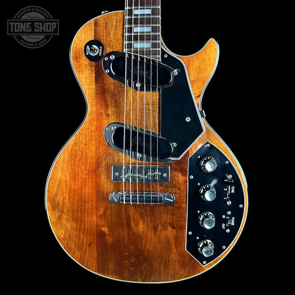 A Gibson ES-175 electric guitar with a natural brown wood finish, black pickguard, and chrome hardware, shown against a solid black background with a Tone Shop watermark in the top left corner.