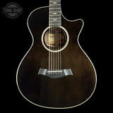 Acoustic guitar with a dark brown finish on a black background, featuring the Tone Shop logo.