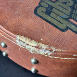 Close-up of a worn leather guitar case with visible stitching and a brand logo.