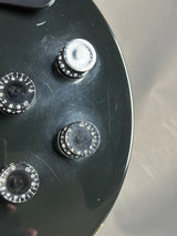 Close-up of a guitar control panel with three knobs on a black background.