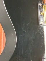 Close-up of a guitar case with visible wear and a strap attached.