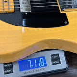 Yellow electric guitar on a digital scale displaying weight.