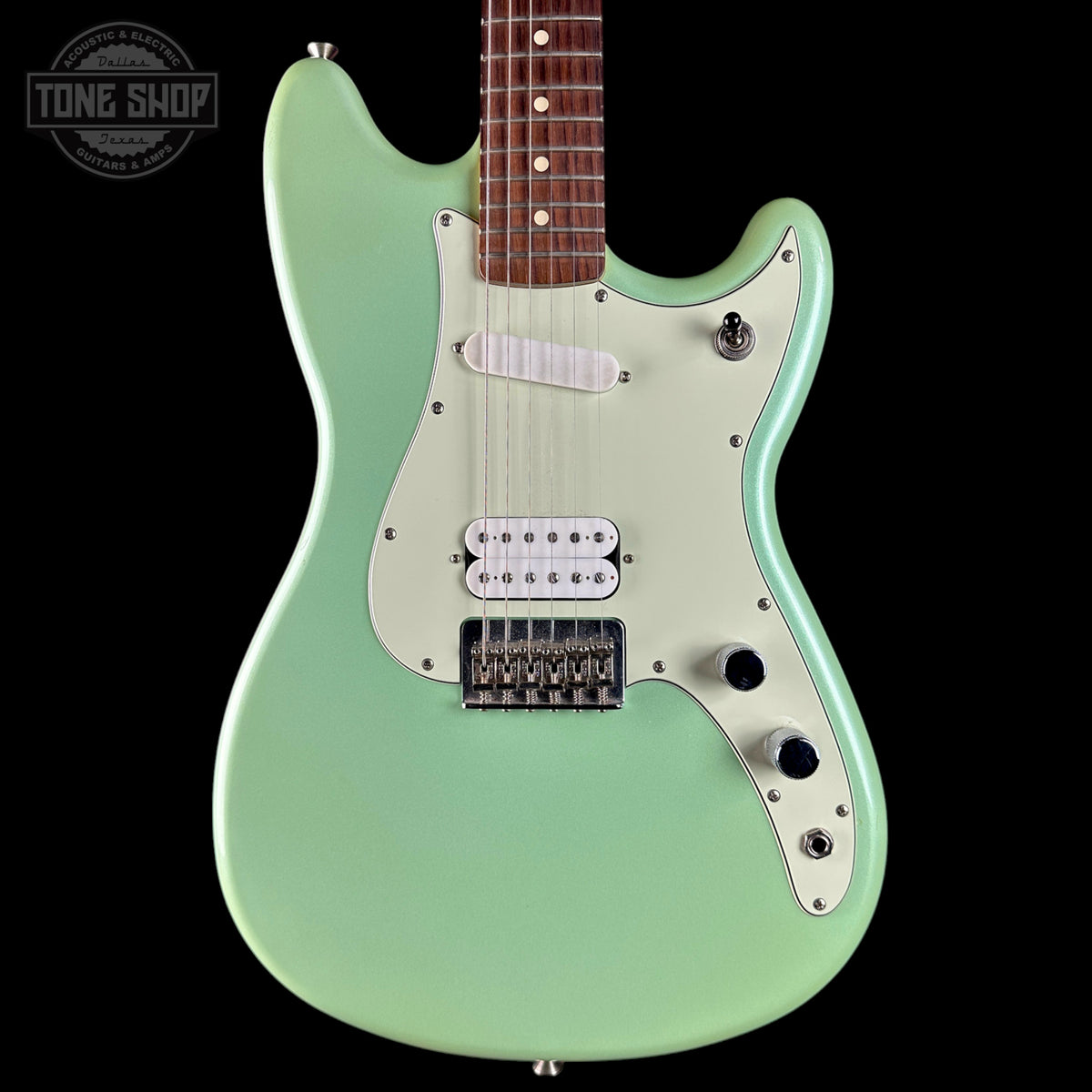 A mint green electric guitar with a white pickguard and silver hardware, shown against a solid black background. A Tone Shop watermark is visible in the top-left corner.