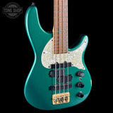 Green electric bass guitar with a wooden neck on a black background, featuring the Tone Shop logo.