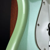 Close-up of a mint green electric guitar body with a white pickguard and visible screw details.