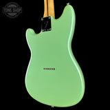 The back of a Fender electric guitar with a mint green body, a natural wood neck, and a black Fender logo plate, shown against a solid black background.