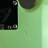 Close-up of a light green guitar body with a black control plate featuring a stylized F-shaped logo and screws.