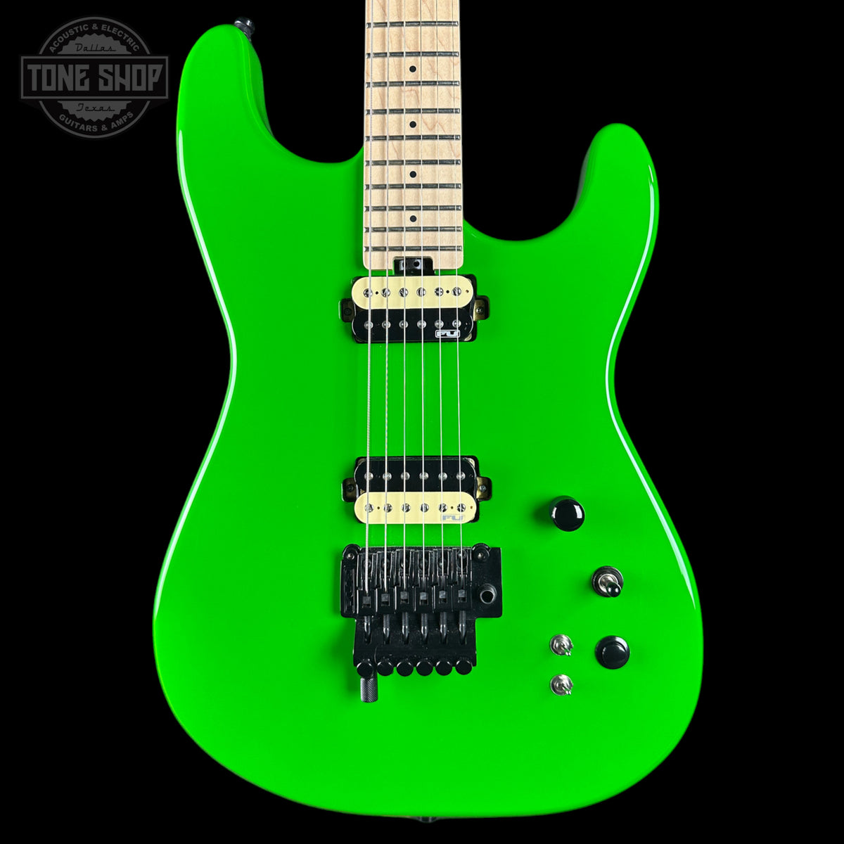 Green electric guitar with a black pickguard on a black background, featuring the 'Tone Shop' logo.