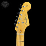 Close-up of a Fender Telecaster electric guitar headstock in a natural maple finish, showing six silver tuning pegs and the Fender logo, set against a solid black background.