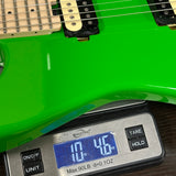 Green electric guitar on a digital scale displaying weight.