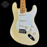 A classic electric guitar with a cream-colored body, a white pickguard, and a natural maple neck, shown against a solid black background with a Tone Shop watermark in the top left corner.