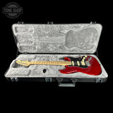 Red electric guitar in a hard-shell case with 'Tone Shop' logo.