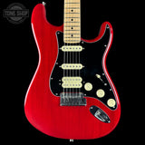 Red electric guitar with a black pickguard on a black background, featuring the Tone Shop logo.