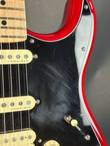 Close-up of a guitar with a red and black body on a gray background