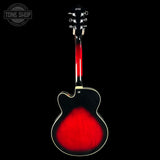 A back view of a Ibanez electric guitar with a glossy black finish and a vibrant red sunburst pattern on the lower half, set against a solid black background with a Tone Shop watermark in the top left corner.