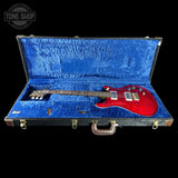 Red electric guitar in a blue case with 'Tone Shop' logo.