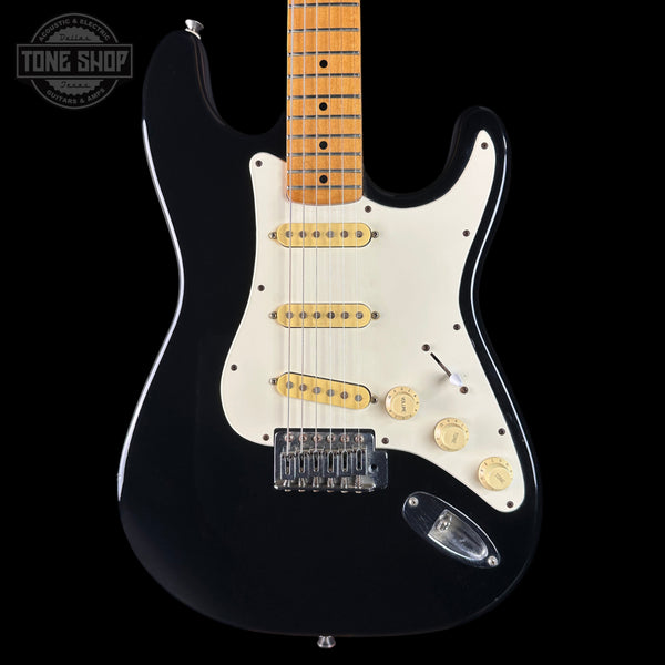 Black electric guitar with a white pickguard on a black background, featuring the Tone Shop logo.