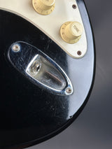 Close-up of a guitar's control knobs and switch on a dark background