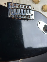 Close-up of a guitar's bridge and headstock with visible wear.