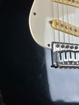 Close-up of a guitar's neck and headstock on a dark surface