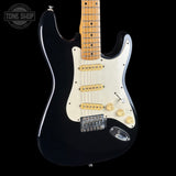 Black electric guitar with a visible brand logo on a black background