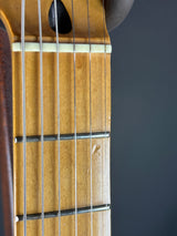 Close-up of a guitar's fretboard and strings against a dark background