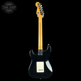 Black electric guitar with a visible brand logo on a black background