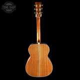 Back view of a wooden acoustic guitar with 'Tone Shop' logo.