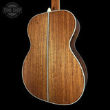Close-up of a wooden acoustic guitar on a black background with 'Tone Shop' logo.