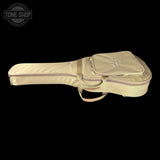 A cream-colored nylon guitar or ukulele gig bag with a zippered main compartment and a front storage pocket, shown against a solid black background. A Tone Shop logo is visible in the top-left corner.