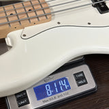 White electric bass guitar on a digital scale displaying weight