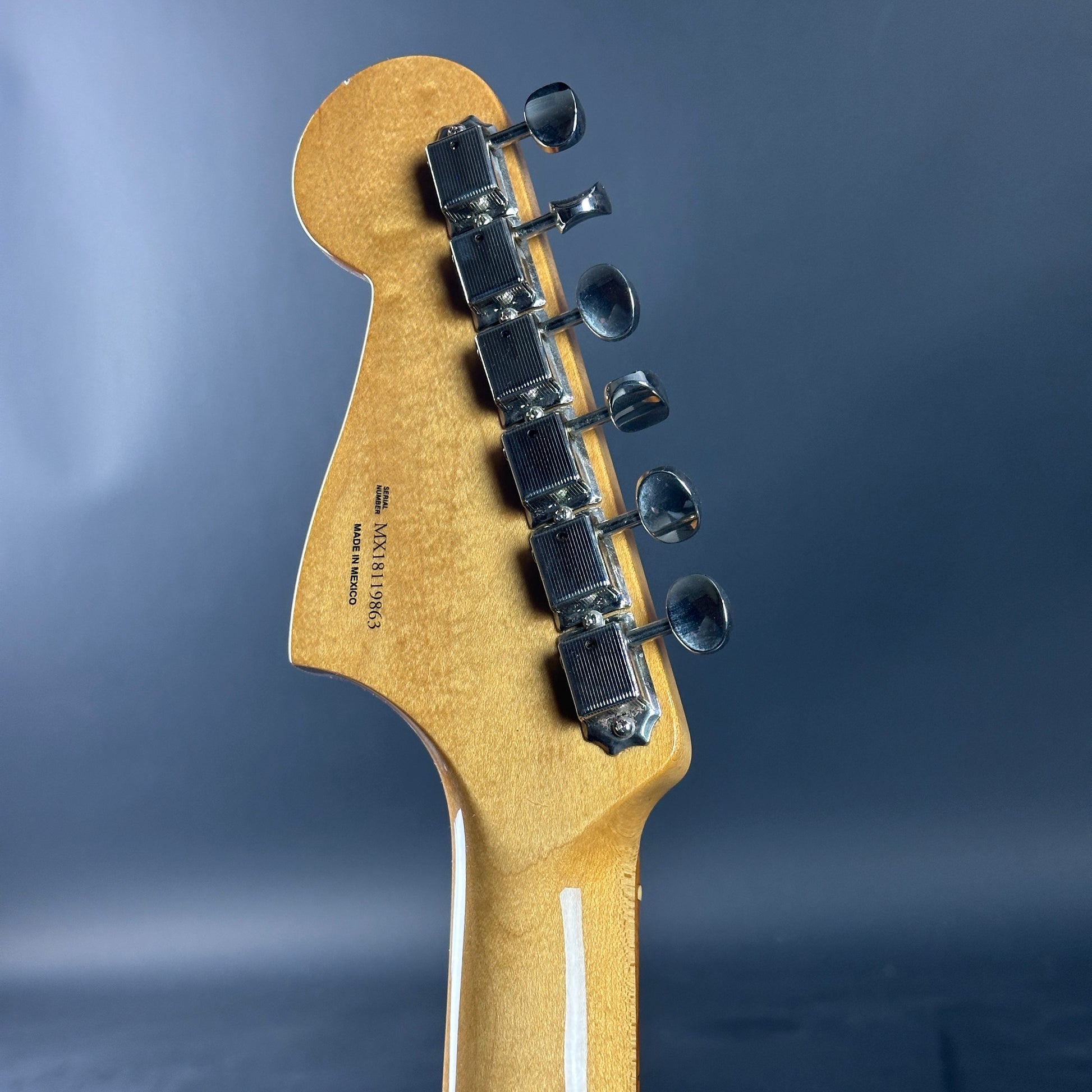 Guitar headstock with tuning pegs on a blue background