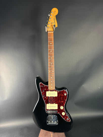 Electric guitar with a black body and red pickguard on a gray background