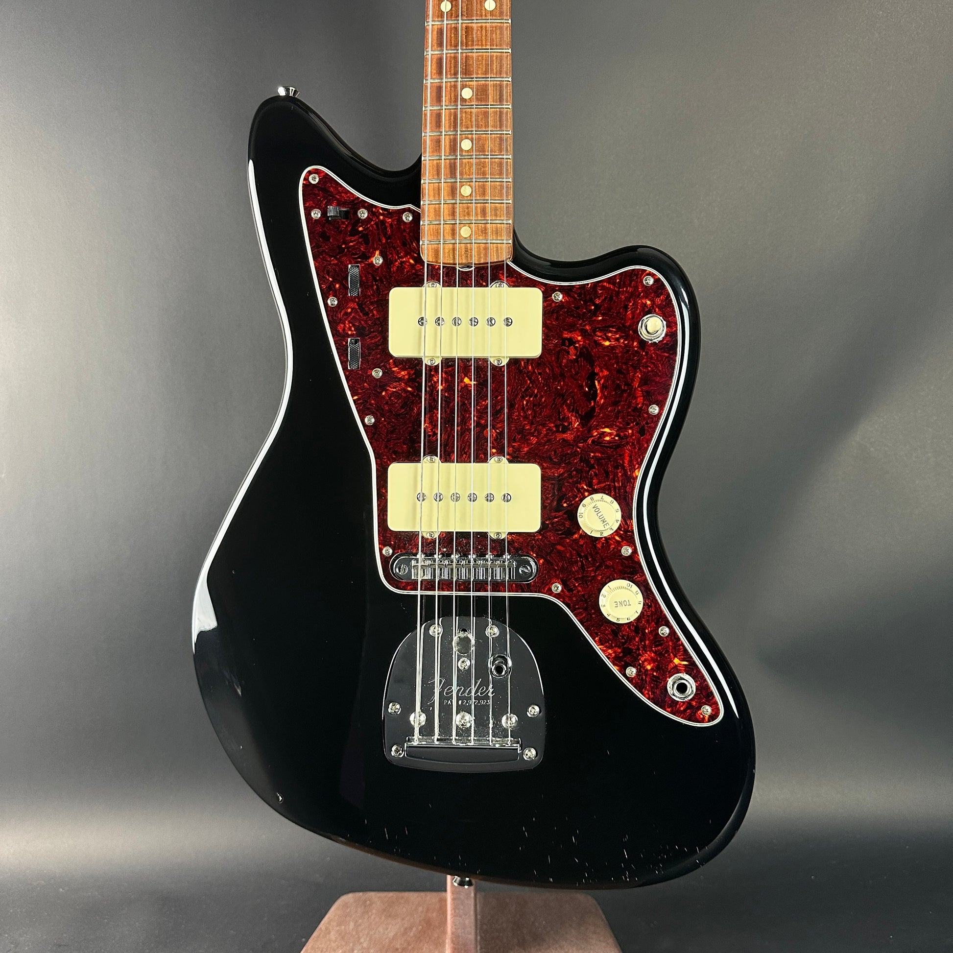 Black electric guitar with red pickguard on a gray background