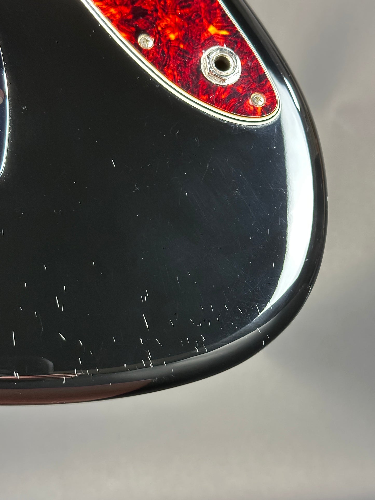 Close-up of a motorcycle tail light with red lens and black casing on a gray background