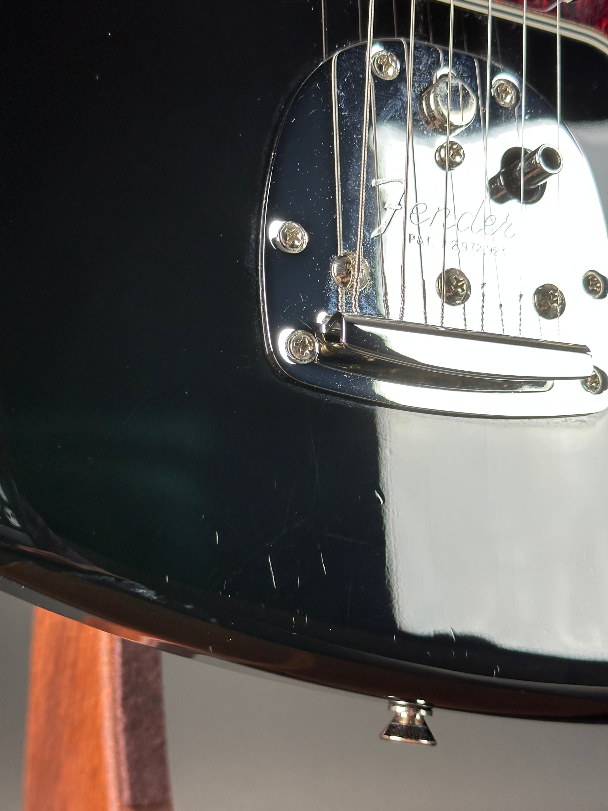 Close-up of a black electric guitar with a metallic pickguard.
