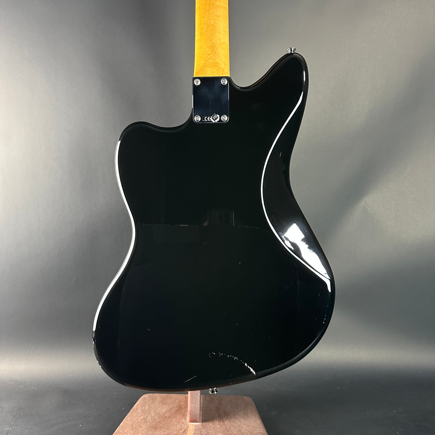 Black electric guitar on a stand against a gray background