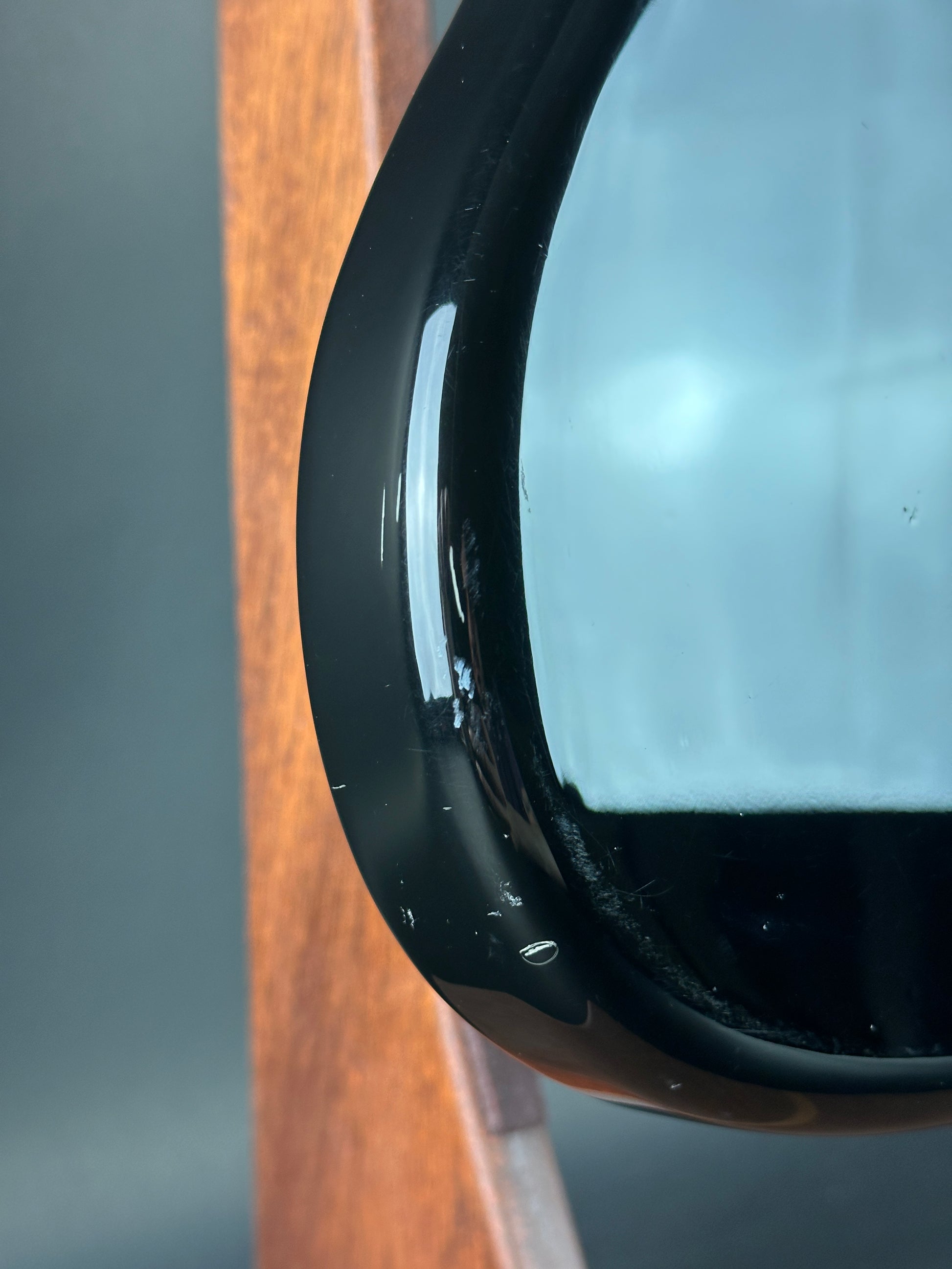 Close-up of a black electronic device on a wooden surface with a blurred background