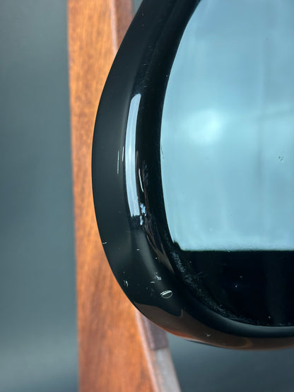 Close-up of a black electronic device on a wooden surface with a blurred background