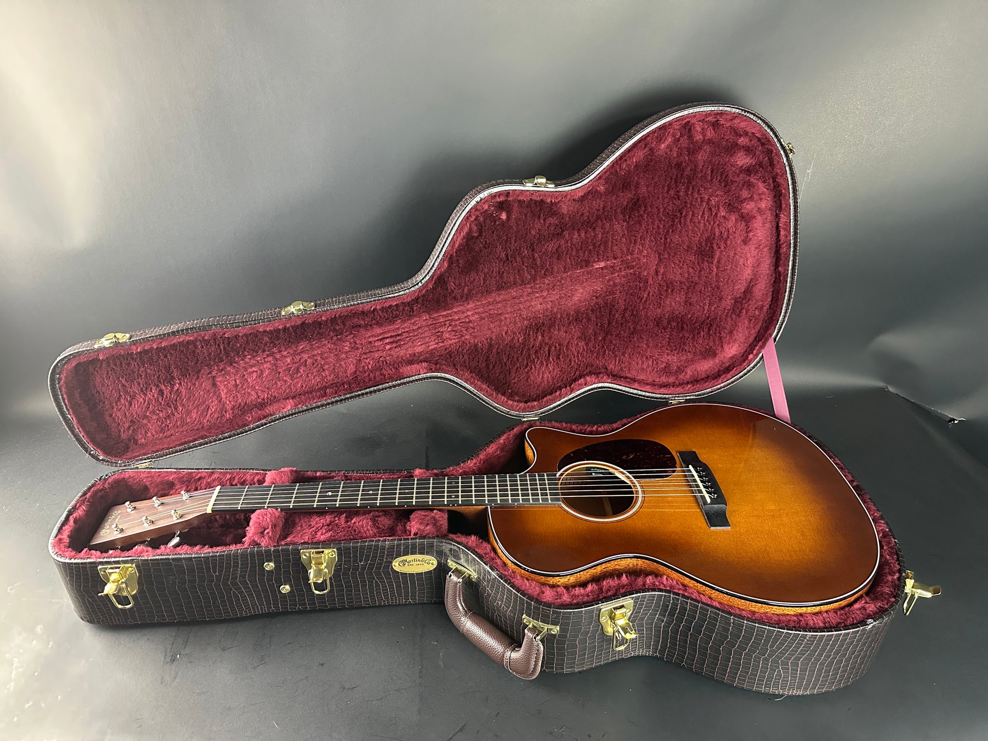 Acoustic guitar in an open case on a gray surface