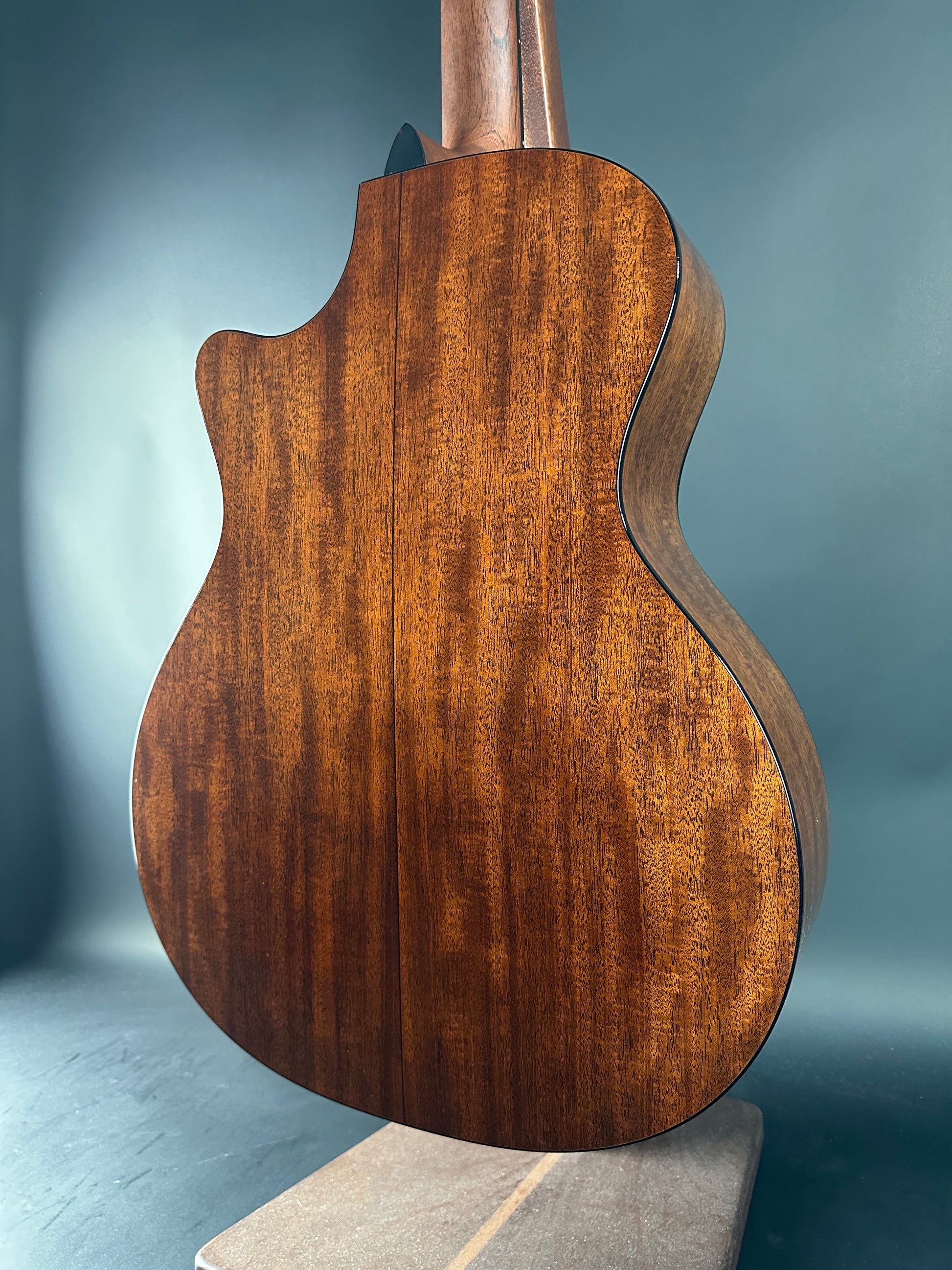 Close-up of a wooden guitar body against a gray background