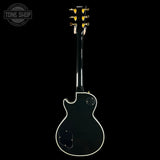 Back view of a black electric guitar with 'Tone Shop' logo.