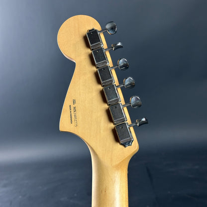 Close-up of a guitar headstock with tuning pegs on a dark background